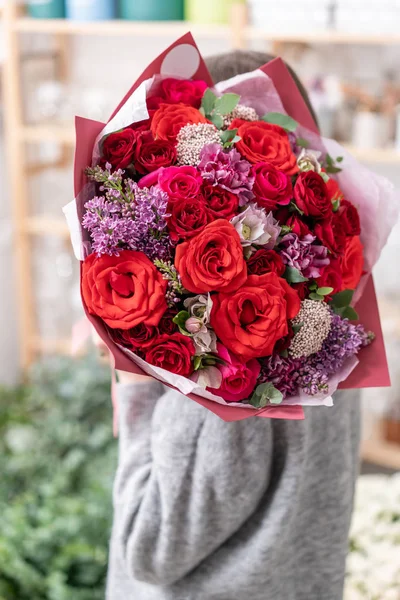Belo buquê de corte fresco de flores mistas na mão da mulher. o trabalho da florista em uma loja de flores. Cor vermelha — Fotografia de Stock