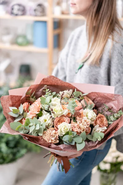 Hermoso ramo fresco cortado de flores mixtas en mano de mujer. el trabajo de la floristería en una florería. Delicado color de tonos pastel — Foto de Stock