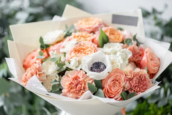 Schöner frisch geschnittener Strauß gemischter Blumen in der Vase auf einem Holztisch. die Arbeit des Blumenhändlers in einem Blumenladen. zarte Pastelltöne Farbe — Stockfoto
