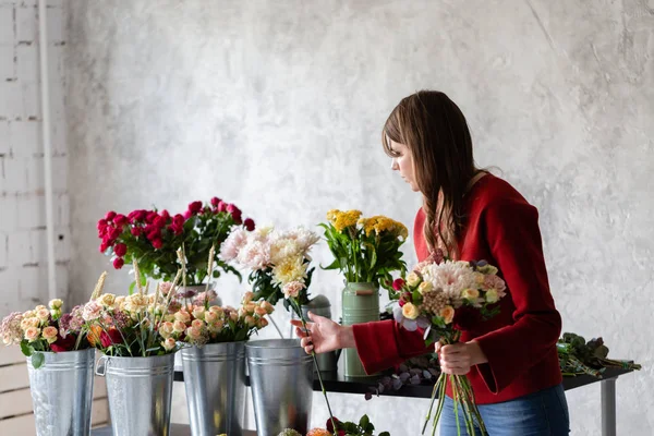 Trabajo florista. Mujer arreglando un ramo con rosas, crisantemo, clavel y otras flores. Un profesor de floristería en clases magistrales o cursos — Foto de Stock