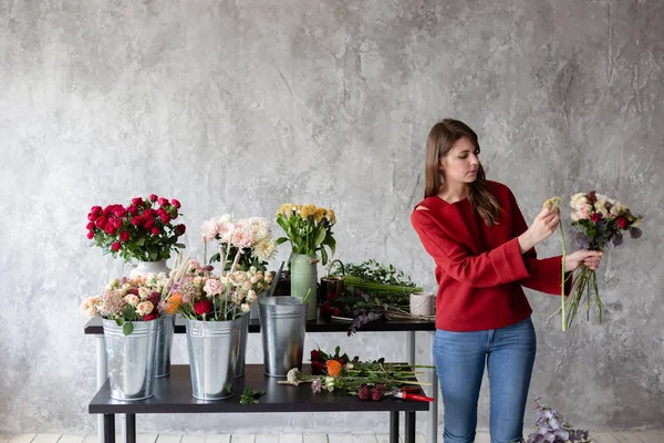 Çiçekçi işyeri. Kadın bir buket gül, kasımpatı, karanfil ve diğer çiçekleri ile düzenlenmesi. Floristik ana sınıfları veya dersleri öğretmeni — Stok fotoğraf