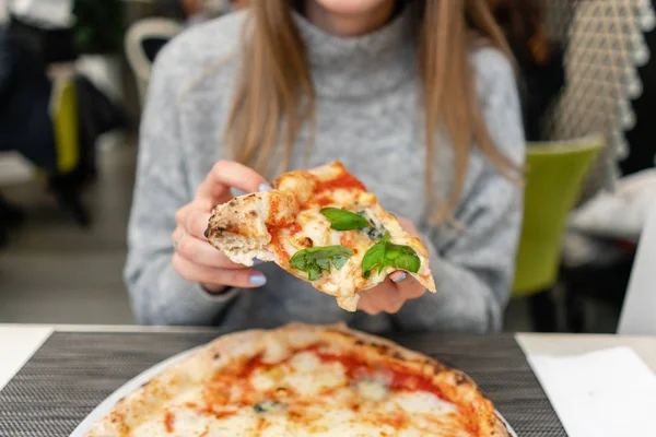 Eine Frau isst neapolitanische Pizza aus dem Holzofen. Mittagessen in einem italienischen Restaurant. Tisch neben einem großen Fenster. Margarita und vier Käse — Stockfoto