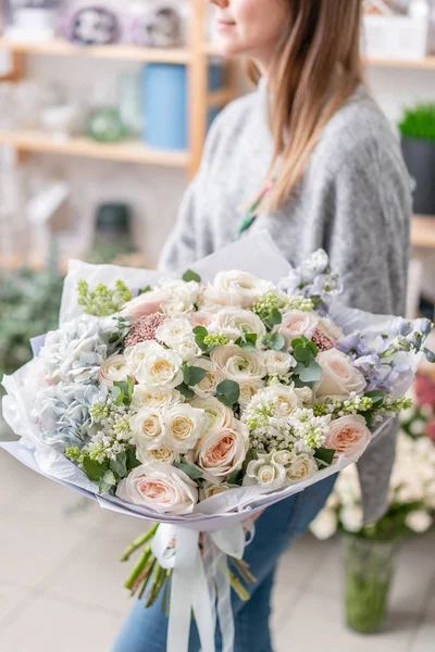 Hermoso ramo fresco cortado de flores mixtas en mano de mujer. el trabajo de la floristería en una florería. Delicado color de tonos pastel — Foto de Stock