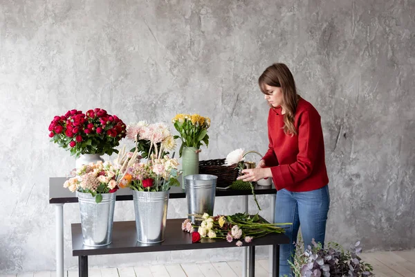 Trabajo florista. Mujer arreglando un ramo con rosas, crisantemo, clavel y otras flores. Un profesor de floristería en clases magistrales o cursos — Foto de Stock