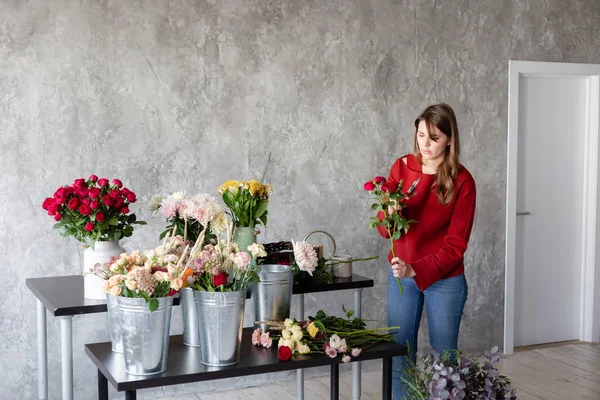 Florist arbetsplatsen. Kvinna att arrangera en bukett med rosor, krysantemum, nejlika och andra blommor. En lärare i blomsterhandlare i mästarkurser eller kurser — Stockfoto