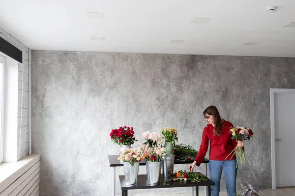 Florist arbetsplatsen. Kvinna att arrangera en bukett med rosor, krysantemum, nejlika och andra blommor. En lärare i blomsterhandlare i mästarkurser eller kurser — Stockfoto