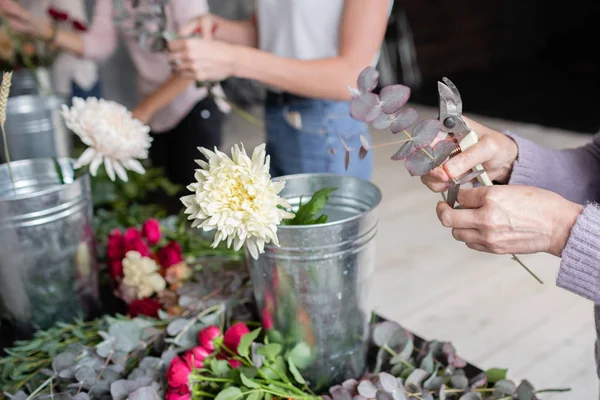 Flores de primer plano en un cubo de metal. Trabajo florista. Mujer arreglando un ramo con rosas, crisantemo, clavel y otras flores. Un profesor de floristería en clases magistrales o cursos — Foto de Stock