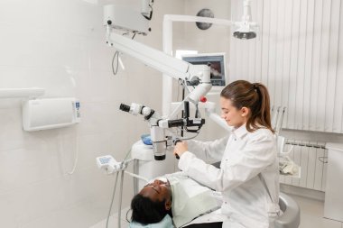 Kadın dişçi Gelişmiş Kullanıcı, diş araçları. Hasta dişlerini incelenmesi için kurulum mikroskop. Diş Kliniği ofisinde. Tıp, diş hekimliği ve sağlık kavramı.