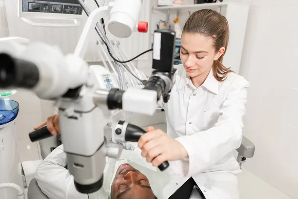 Dentista femenina usuario avanzado, herramientas dentales. Instalación de microscopio para examinar los dientes de sus pacientes. en el consultorio dental. Concepto de medicina, odontología y salud . — Foto de Stock