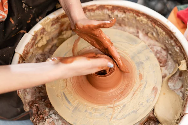 Mani artigianali che fanno vasellame. Donna che lavora alla ruota del vasaio. Negozio di famiglia scolpisce pentola da argilla vista superiore . — Foto Stock