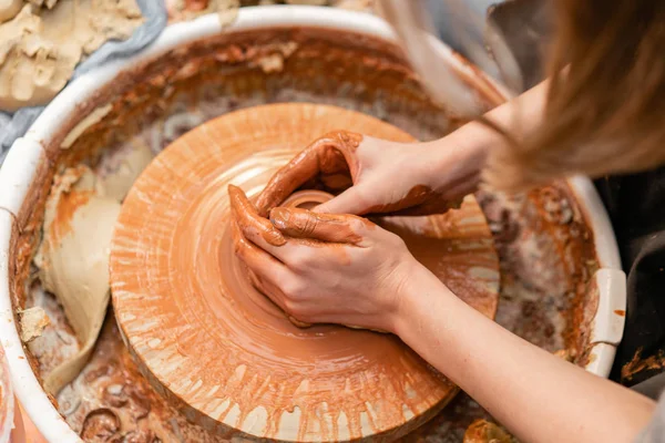 Mãos de artesão fazendo tigela de cerâmica. Mulher a trabalhar na roda de oleiro. Família loja de negócios esculpe pote de argila vista topo . — Fotografia de Stock