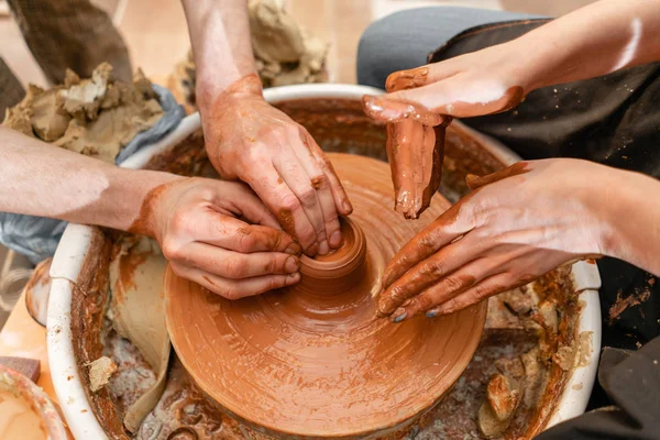 Master ceramist geeft les aan student.Master ceramist geeft les aan student. Ambachtelijke handen die pottenbakkerskom maken. Vrouw die aan pottenbakkerswiel werkt. Familie winkel beeldhouwt pot van klei uitzicht top. — Stockfoto