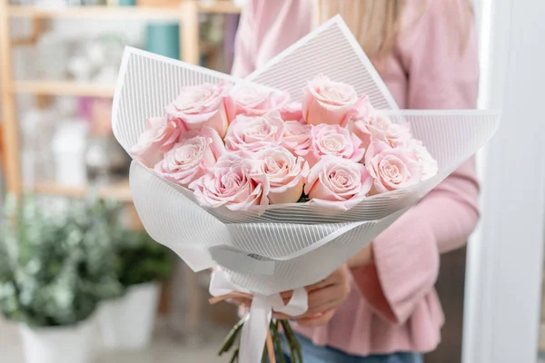 Buquê de rosas em mãos de mulheres. Um bando de rosa pálido. o conceito de uma florista em uma loja de flores. Papel de parede . — Fotografia de Stock