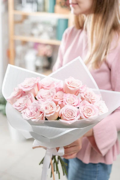 Buquê de rosas em mãos de mulheres. Um bando de rosa pálido. o conceito de uma florista em uma loja de flores. Papel de parede . — Fotografia de Stock