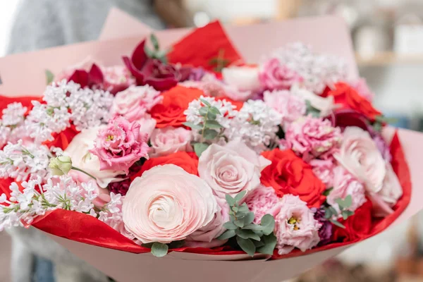 Beautiful fresh cut bouquet of mixed flowers in woman hand. the work of the florist at a flower shop. Red and pink color — Stock Photo, Image