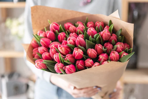Young beautiful woman holding a spring bouquet of red tulips in her hand. Bunch of fresh cut spring flowers in female hands — Stock Photo, Image