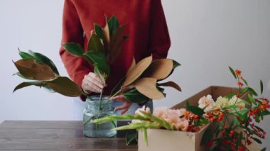 Kadın Çiçekçi Çiçek bir cam vazo ve yeni bir çiçek düzenlemeleri yapma koyar. Kadın güzel buket vazo içinde oluşturmak için taze çiçekler kutusundan seçmek. Çiçek Dükkanı kavramı