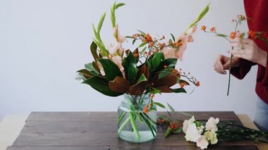 Kadın Çiçekçi Çiçek bir cam vazo ve yeni bir çiçek düzenlemeleri yapma koyar. Kadın güzel buket vazo içinde oluşturmak için taze çiçekler kutusundan seçmek. Çiçek Dükkanı kavramı
