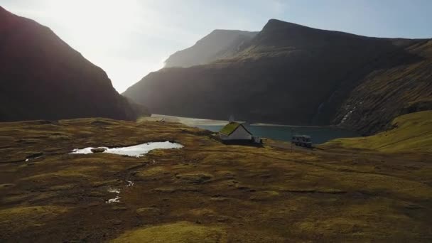 Petite église de village à Saksun et un lac voisin situé sur l'île de Streymoy, îles Féroé, Danemark. Tirer sur un quadrocopter de drone , — Video