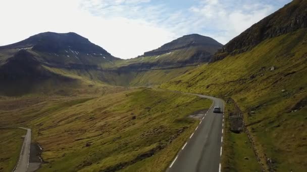 Dinamarca, Islas Feroe - 14 de mayo de 2017: Islas del Atlántico Norte al atardecer. El coche va en la carretera a lo largo de la montaña, Disparos desde el quadrocopter — Vídeos de Stock