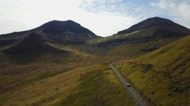 Danimarka, Faroe Adaları - Mayıs, 14 2017: Kuzey Atlantik Adaları'nde Günbatımı. Dağ, yolda araba gider quadrocopter çekim