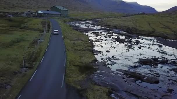 Danemark, Îles Féroé - 14 mai 2017 : Îles de l'Atlantique Nord au coucher du soleil. La voiture part sur la route le long de la côte, prise de vue depuis le quadrocopter — Video