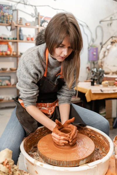 Donna felice che lavora sulla ruota della ceramica in laboratorio di ceramica. Negozio di famiglia scolpisce pentola da argilla vista superiore . — Foto Stock
