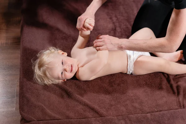 Masaje de bebé. Madre o terapeuta hace masajes a su bebé en casa. Concepto de salud y medicina. Niño rubio —  Fotos de Stock