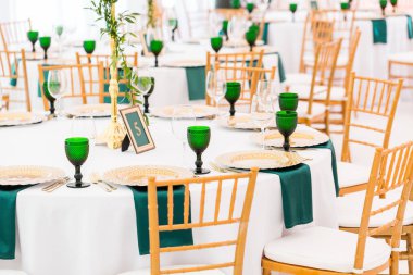 Düğün Yemeği, Konuklar için hazır için çadır iç. Yuvarlak Ziyafet masa servis. Altın yemekleri, yeşil şarap bardakları ve peçeteler. Kavram catering.