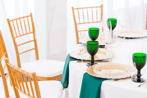Interno della tenda per la cena di nozze, pronto per gli ospiti. Servito tavolo rotondo per banchetti. Piatti d'oro, bicchieri di vino verde e tovaglioli. Concetto di catering . — Foto Stock