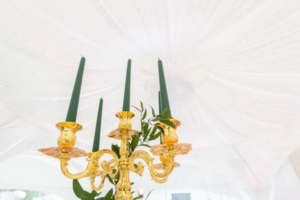 緑の蝋燭と黄金のシャンデリア。ケータリングのコンセプトです。結婚式のディナー、ゲストの準備のためのテントの内部。ラウンド バンケット テーブルを提供しています. — ストック写真