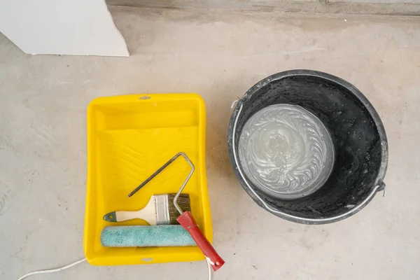Малярський пензлик, валик і клей на бетонній поверхні. Композиційні інструменти для ремонту будинку та ремонту інтер'єру в приміщенні . — стокове фото