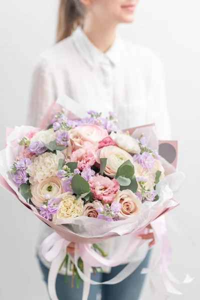 Hermoso ramo fresco cortado de flores mixtas en mano de mujer. el trabajo de la floristería en una florería. Delicado color de tonos pastel — Foto de Stock