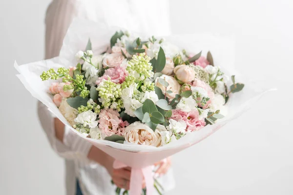 Hermoso ramo fresco cortado de flores mixtas en mano de mujer. el trabajo de la floristería en una florería. Delicado color de tonos pastel —  Fotos de Stock