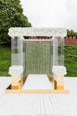 Düğün töreni, lüks dekor için kristal süslemeleri. Arka plan yeşil çim üzerinde şeffaf boncuk zincirlerle süslenmiş güzel kemer