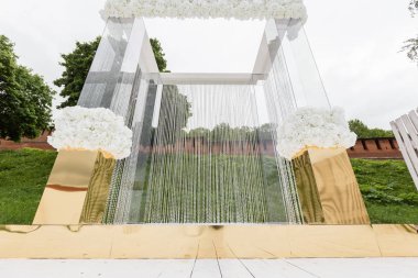 Düğün töreni, lüks dekor için kristal süslemeleri. Arka plan yeşil çim üzerinde şeffaf boncuk zincirlerle süslenmiş güzel kemer