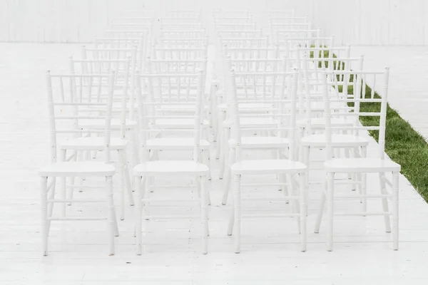 Satır boş beyaz sandalye ahşap bir yere oturma. Düğün töreni açık havada çiçeklere koltukları — Stok fotoğraf