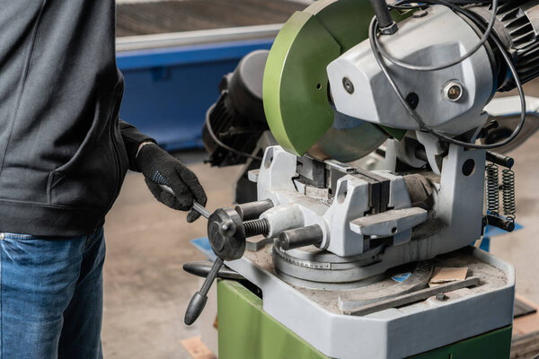 worker cuts a piece of material with a circular saw machine. Industrial engineer working on cutting a metal and steel with compound mitre saw with sharp, circular blade