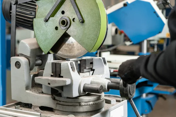 Trabalhador corta um pedaço de material com uma máquina de serra circular. Engenheiro industrial trabalhando no corte de um metal e aço com serra de mitra composta com lâmina circular afiada — Fotografia de Stock