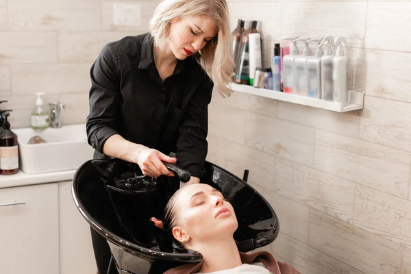 Güzel kız bir güzellik salonunda saçlarını kestirmen önce yıkar. saç Kuaför yıkama. profesyonel şampuan. stilist Kuaför — Stok fotoğraf