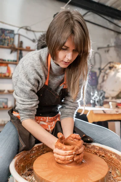 Gelukkige vrouw die werkt op potter wiel in de pottenbakkerij. Familiebedrijf winkel beeldhouwt pot van klei weergave boven. — Stockfoto