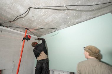drywall yükleme, duvar hizalama. Ölçüm yenileme sırasında lazer. Ve inşaat araçları. Kırmızı lazer ışık satır düzey ölçü birimi.