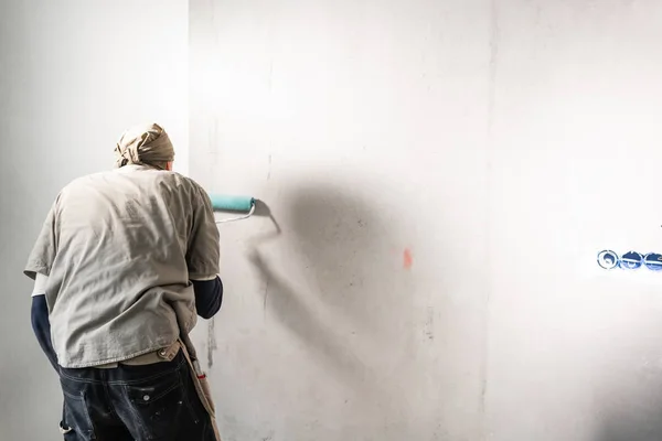 젊은이, 노동자 붙이기를 콘크리트 벽에 월페이퍼. 아파트를 복구 합니다. 홈 리 모델링 개념입니다. 화이트 벽지 페인트에 대 한 — 스톡 사진