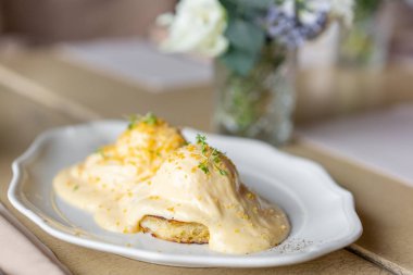 Yumurta Benedict sıcak tost çörek. İki yumurta lezzetli Hollandaise sosu. Hafif sabah restoranda masada kahvaltı.