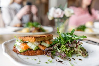 Fransız tost börek, somon ve salatalık ile sandviç. Hafif sabah kahvaltı, restoranda masada taze sıcak hamur işleri