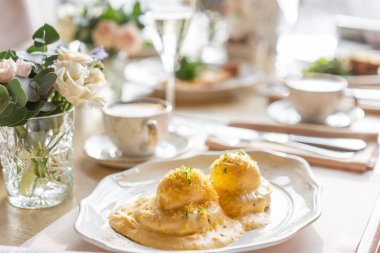 Yumurta Benedict sıcak tost çörek. İki yumurta lezzetli Hollandaise sosu. Hafif sabah restoranda masada kahvaltı.