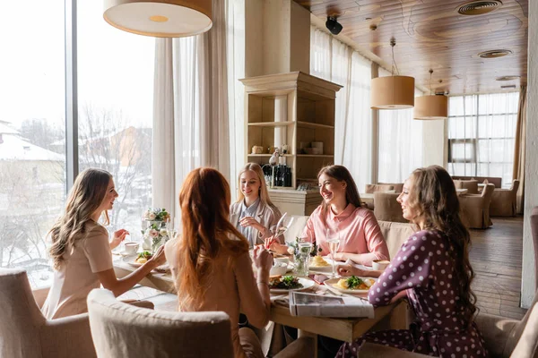 Pět žen. Portrét mladých lidí snídat u stolu v restauraci. Šampaňské pro snídani. Rozhovor a smích, živá komunikace — Stock fotografie