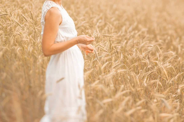Junge blonde Frau steht auf goldenem Weizenfeld und berührt Weizenähren an einem sonnigen Tag. Natur genießen. schöne Mädchen in den Strahlen des Sonnenlichts. Sonnenlicht. — Stockfoto