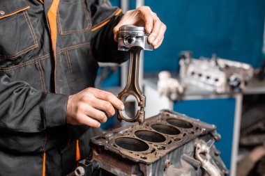 Motor için yeni bir piston tutan araba tamircisi, revizyon.. Motorlu bir onarım standı ile piston ve otomotiv teknolojisinin bağlantı çubuğu. Bir araba tamircisi iç.