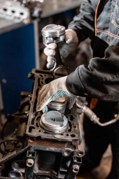 クローズアップ車のメカニックエンジンのための新しいピストンを保持し、オーバーホール...自動車技術のピストンおよび連結の棒が付いている修理立場のエンジン。車の修理店のインテリア. — ストック写真